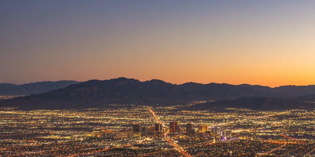El resplandeciente valle desértico de Las Vegas al anochecer, con las torres de neón del Strip alzándose sobre el Mojave
