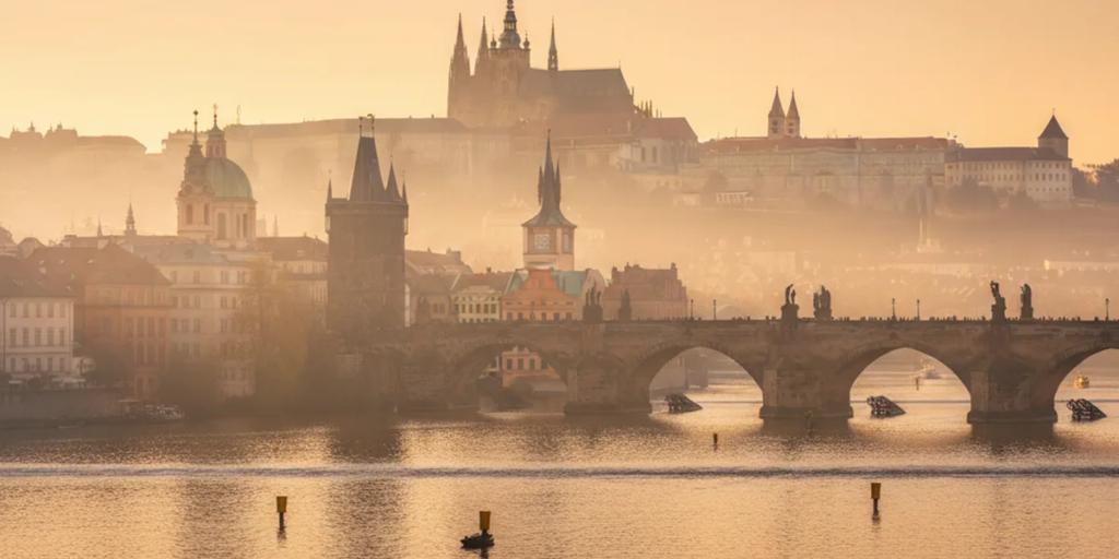 Las estatuas del Puente de Carlos y el Castillo de Praga emergiendo entre la niebla matinal
