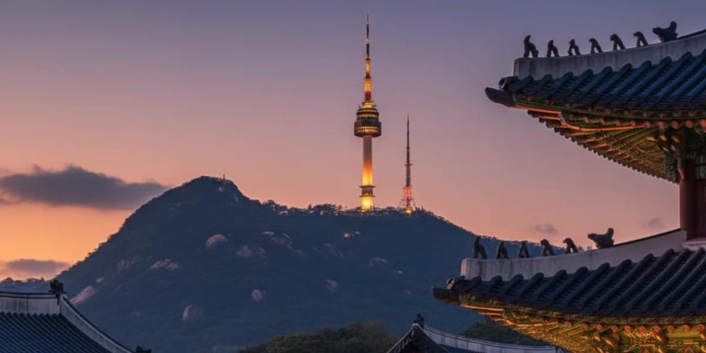 Los tejados del palacio Gyeongbokgung en primer plano con la N Seoul Tower alzándose sobre Namsan al fondo